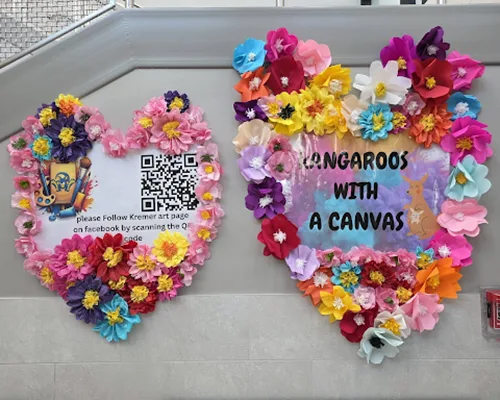 A photo of two heart shaped pieces of art made of flowers. One has a QR code and the other says Kang…