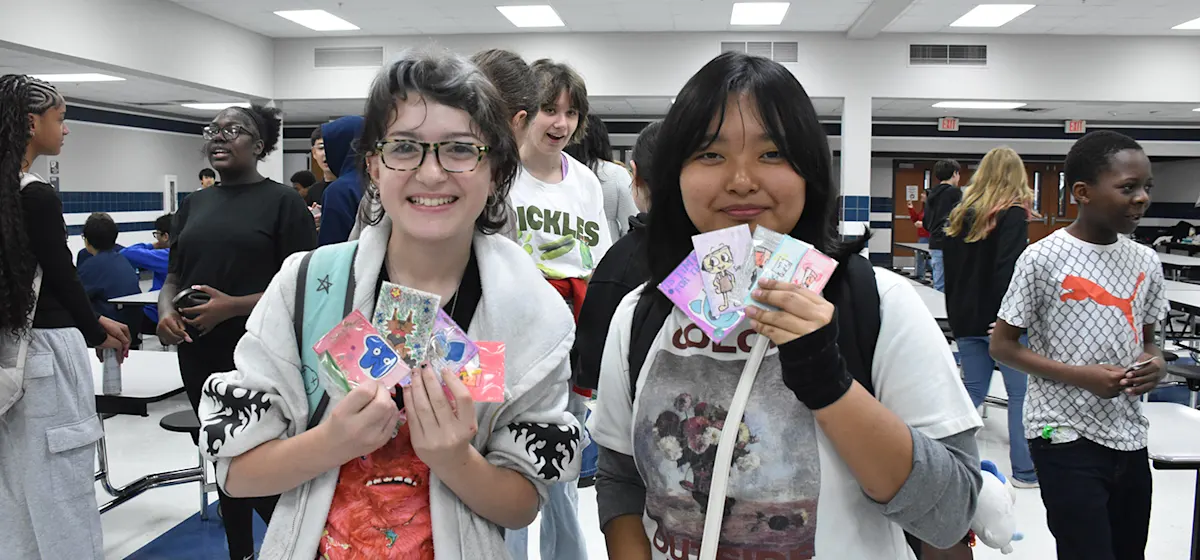 Two Burnett students holding up their trading cards.