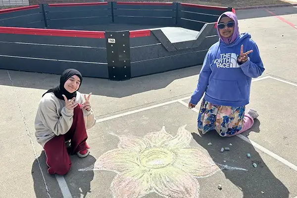 Two Draper students posing with their chalk artwork.