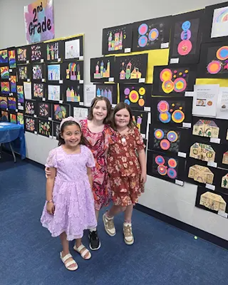 Three Kreymer students posing in front of the school created artwork that has been hung on a classro…