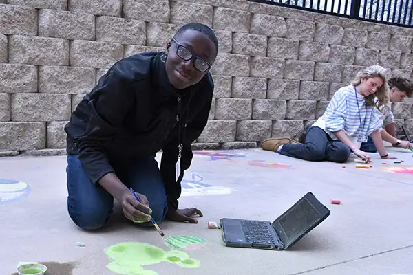 A WEHS student working on his chalk art outside the school.