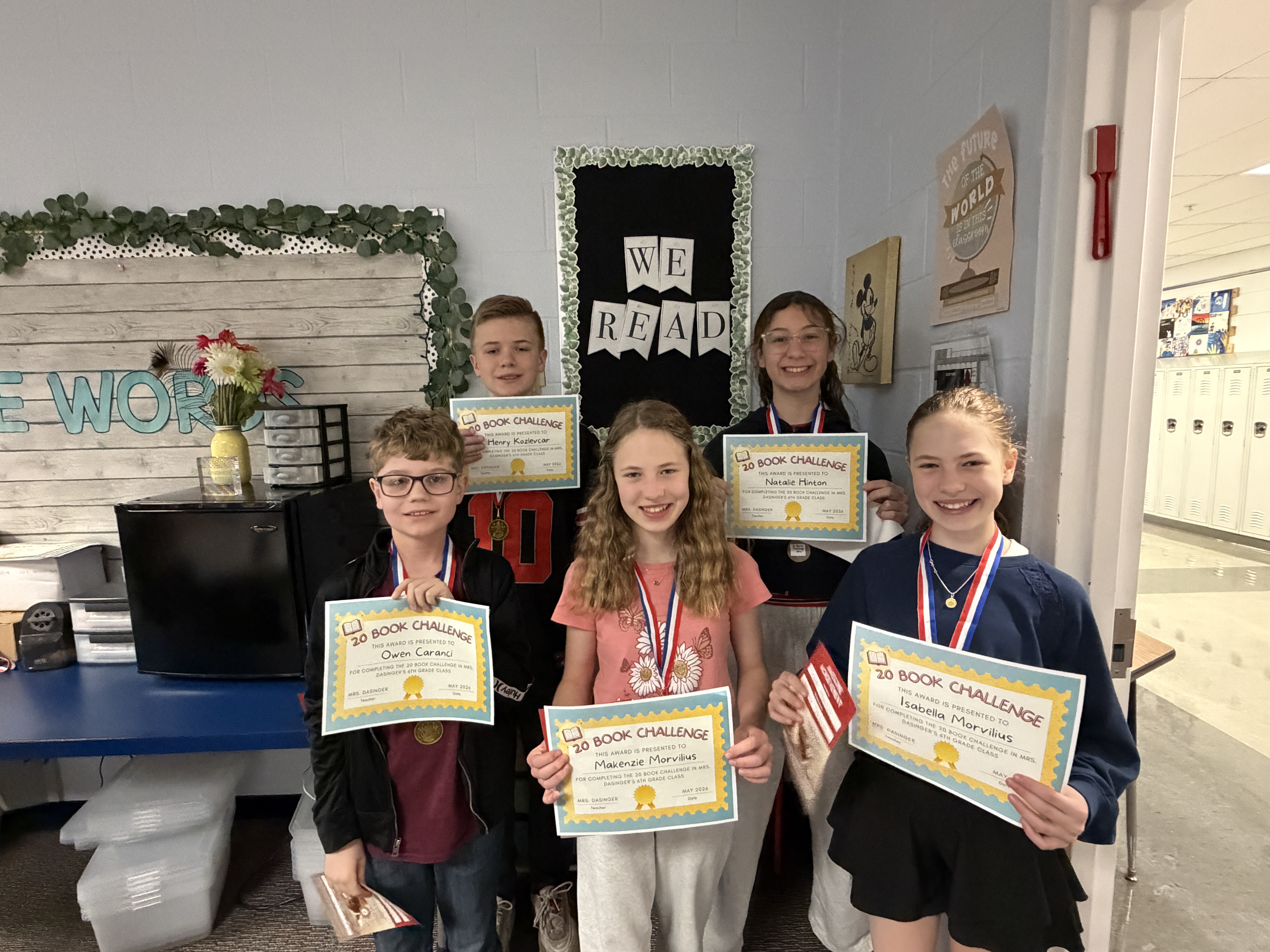 Six students proudly display their '20 Book Challenge' certificates and medals in a classroom.